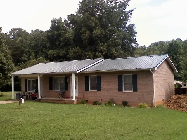 Gray metal roof on a brick ranch house with a side carport in Prairie City