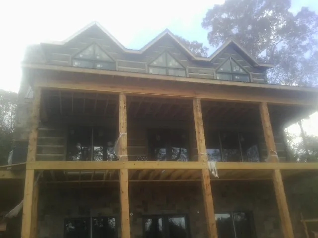 Dormers and porch framing on a large log home under construction — Roof Coating work by our crew in Prairie City