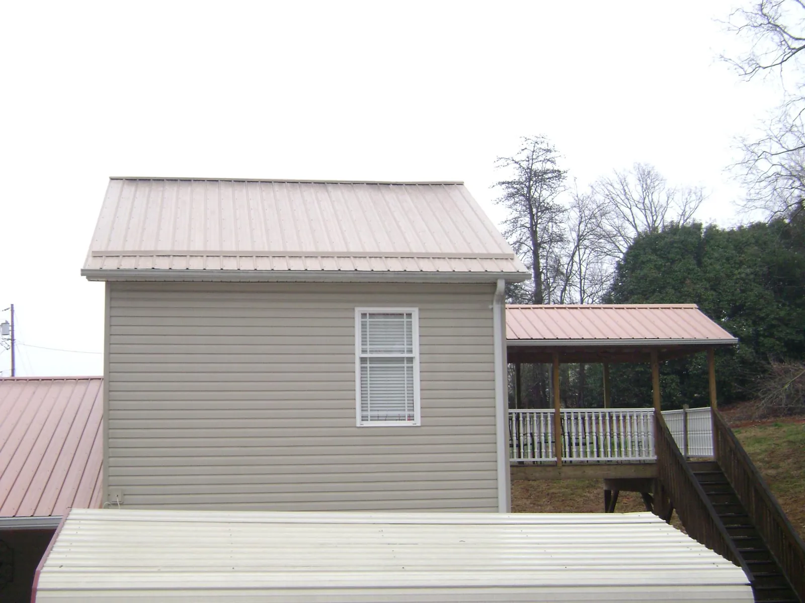 Tan metal roofs on a two story addition and attached porch, from a Roof Replacement job in Prairie City