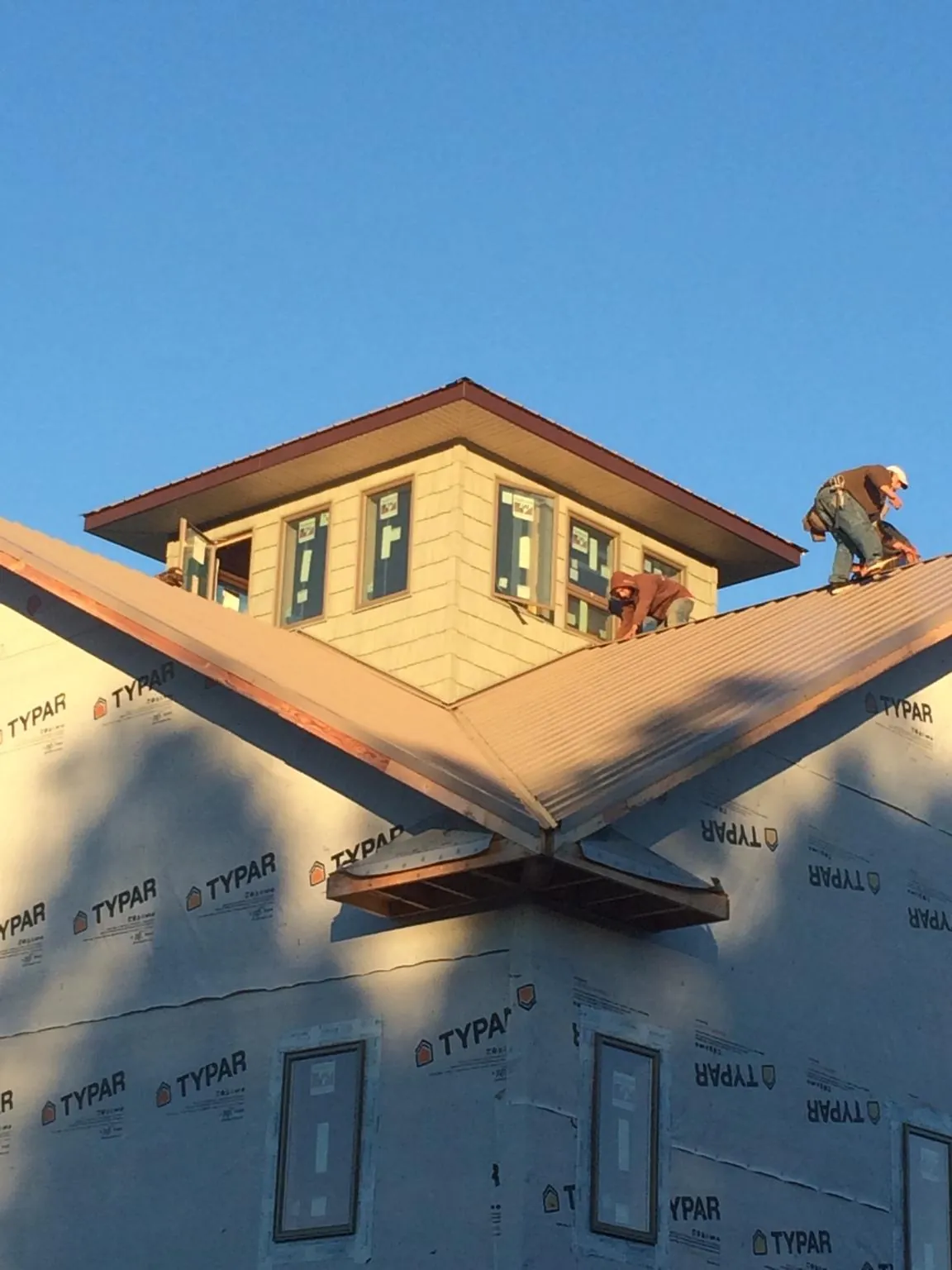 Roofers working around a rooftop cupola on a new metal roof at sunset — Roof Waterproofing in Prairie City by Roofing Brothers